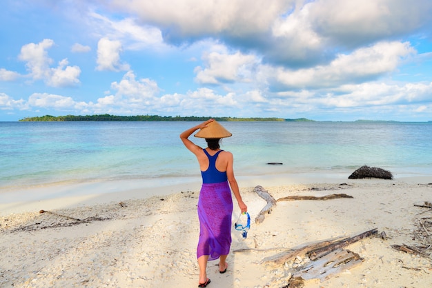 La tenuta della donna che si immerge maschera a disposizione che cammina sulla spiaggia tropicale