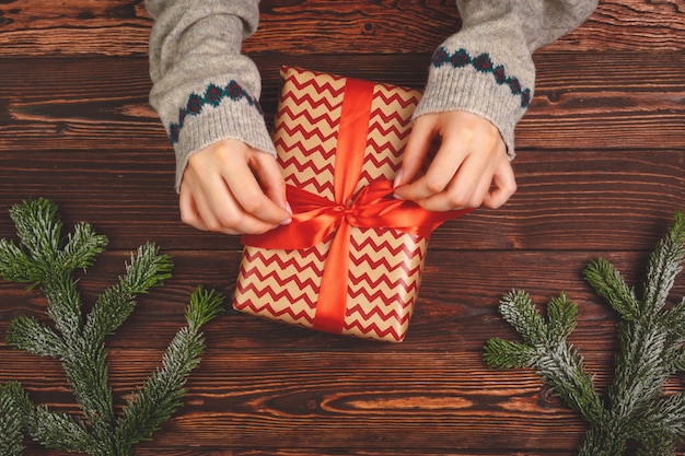 La tenuta della donna ha avvolto regalo di Natale in sue mani, vista da sopra