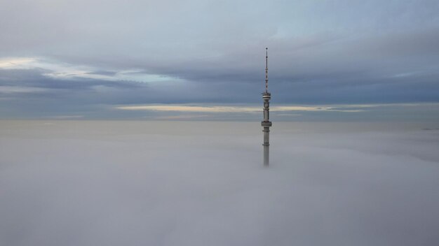 La torre della televisione guarda fuori dalle nuvole al tramonto. Vista dall'alto da un drone su un doppio strato di nuvole.