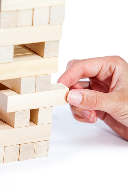 La torre di blocchi di legno e la mano dell'uomo prendono un blocco