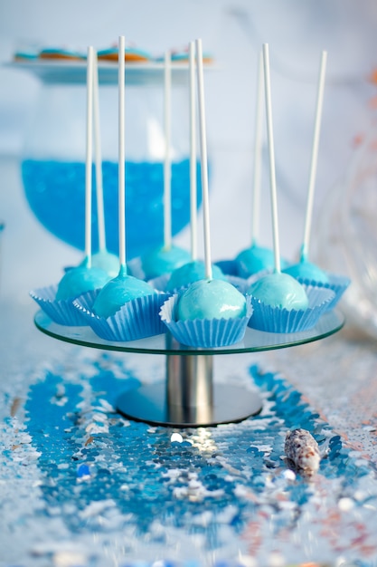 La torta blu si apre sul panno d'argento. Tema del tempo di mare sul candy bar della festa.