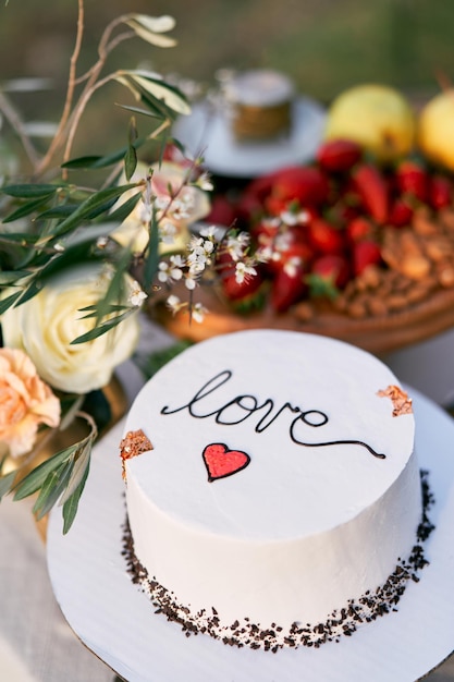 La torta di nozze è sul tavolo accanto al bouquet di fiori.