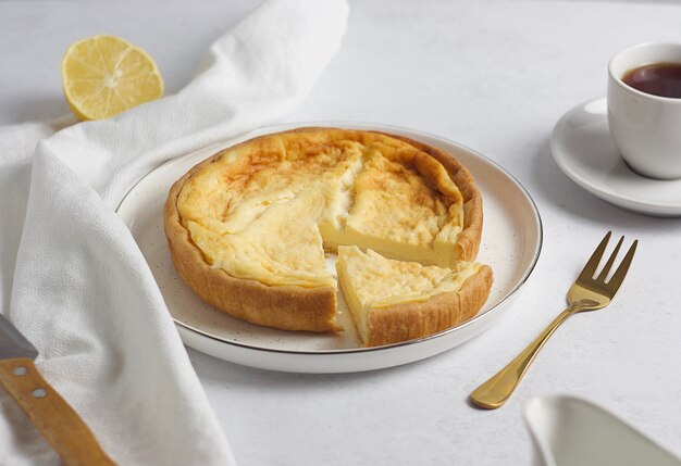 La torta di panna acida è sul tavolo. Accanto c'è una tazza di tè, una forchetta e un asciugamano. Colazione.