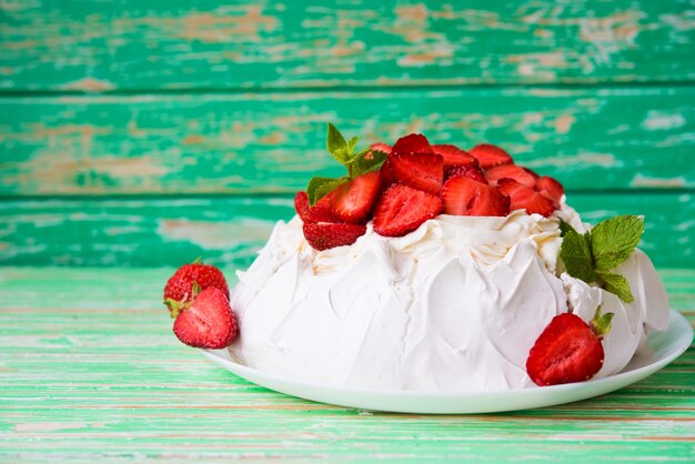 La torta di Pavlov con fragole e panna su fondo rustico, messa a fuoco selettiva, spazio copia