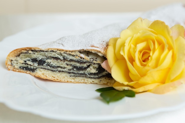 La torta di semi di papavero si trova su un piatto decorato con un fiore vivo