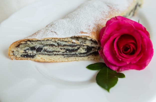 La torta di semi di papavero si trova su un piatto decorato con un fiore vivo