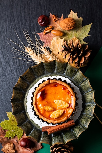 La torta di zucche rustica organica casalinga di concetto dell'alimento di autunno decorare dal permesso di autunno su fondo nero con lo spazio della copia