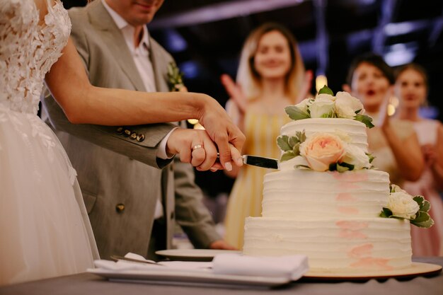 La torta nuziale. Gli sposi hanno tagliato un pezzo di torta con un coltello. Le mani degli sposi