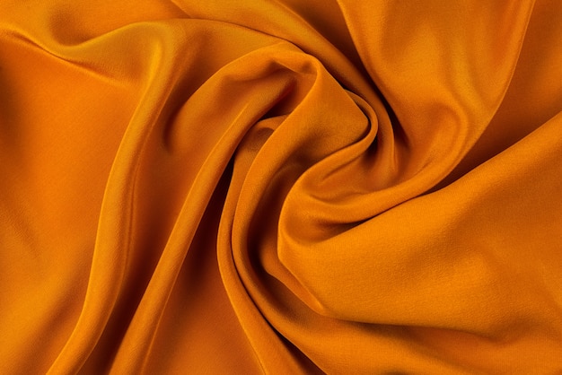 La trama del tessuto di seta dorata o satinata di lusso può essere utilizzata come sfondo astratto. Vista dall'alto.