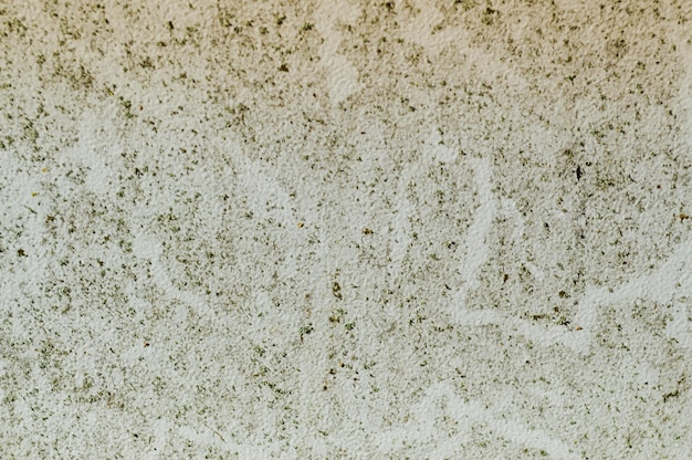 La trama del vecchio muro squallido in cemento di pietra con crepe e scheggiature con imbiancatura