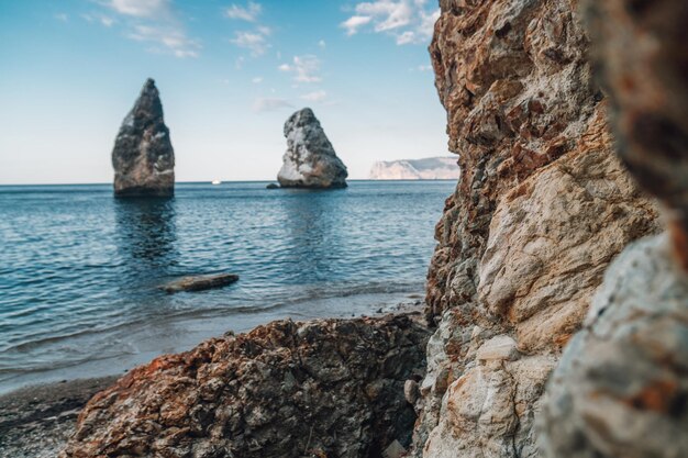 La tranquilla vista sul mare sulla spiaggia durante il tramonto con la scogliera vulcanica rocciosa è illuminata dal caldo tramonto