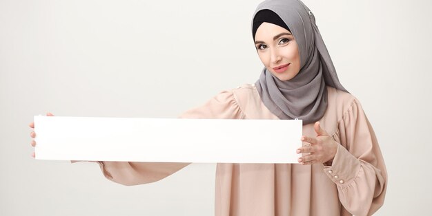 La tua offerta qui. Donna in hijab con striscione bianco