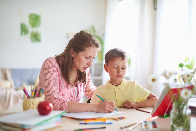 La tutor madre aiuta il figlio a fare lezioni. correggere l'errore nelle lezioni a casa.