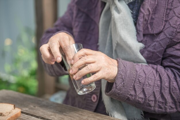 La vecchia beve l'acqua e mangia il pane a un vecchio tavolo di legno in un giardino