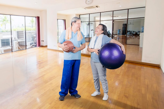 La vecchia coppia felice tiene palla da basket e pilates