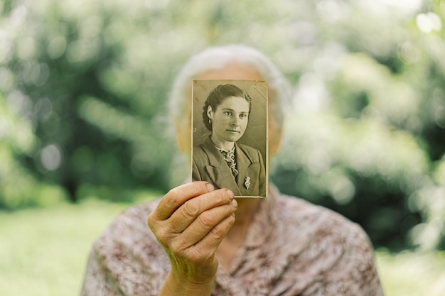 La vecchia ricorda la sua giovinezza. La nonna conserva la sua foto in gioventù. Ricordi. Vecchie foto d'epoca