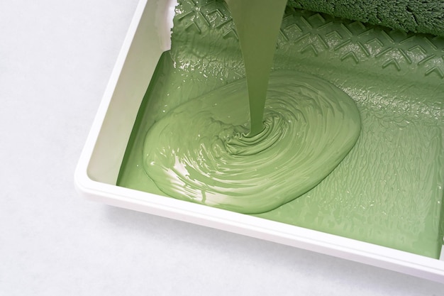 La vernice verde viene versata nel vassoio della vernice