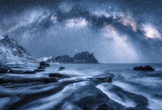 La Via Lattea sopra la costa del mare ghiacciato e le montagne innevate