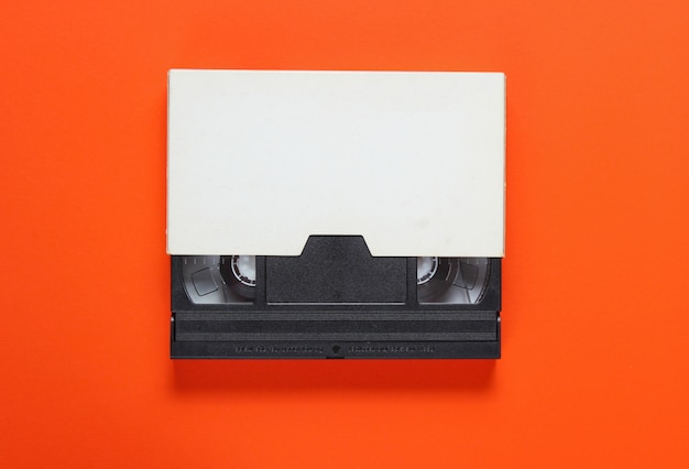 La videocassetta in una custodia di carta su sfondo arancione