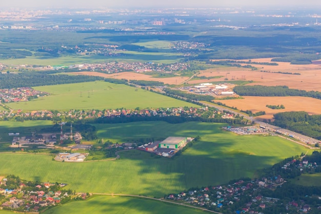 La vista aerea dei campi ospita edifici o una piccola città in una bella giornata estiva con un paesaggio verde