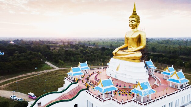 La vista aerea di grande statua dorata di Buddha al sole aumenta, campagna della Tailandia