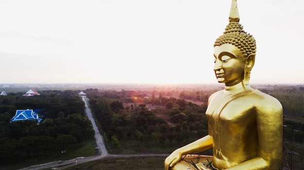 La vista aerea di grande statua dorata di Buddha al sole aumenta, campagna della Tailandia