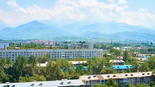 La vista dall'alto della città di Almaty in Kazakistan. Case residenziali, montagne, cielo, alberi, paesaggio estivo