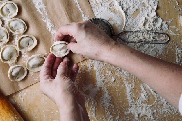 La vista dall'alto della donna piega gli gnocchi crudi su un foglio di pergamena