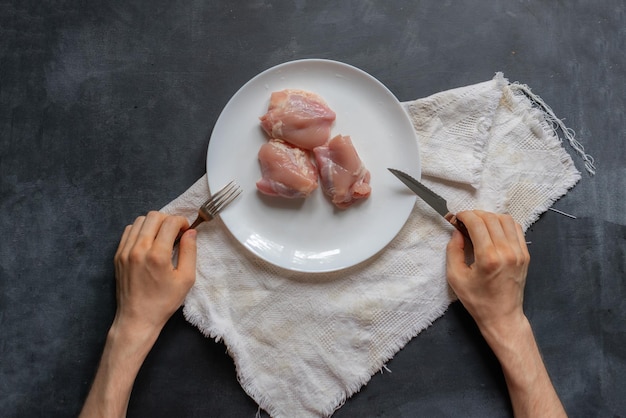 La vista dall'alto delle mani della persona mangia carne cruda non cotta nel piatto