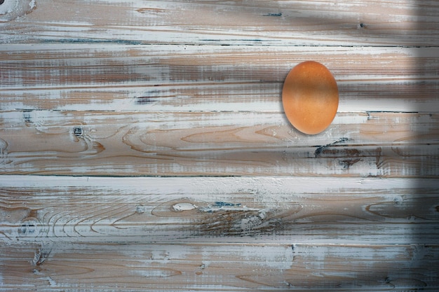 La vista dall'alto di un uovo di gallina all'angolo di un tavolo di legno ha aggiunto spazio per la copia del testo