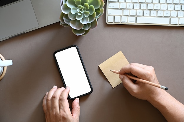 La vista dall&#39;alto ha sparato dell&#39;uomo che scrive la nota appiccicosa e che per mezzo del telefono cellulare