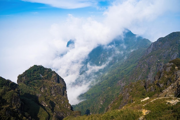 La vista dalla cima del monte Fansipan nella catena montuosa di Sapa Hoang Lien Son Le cime delle montagne rocciose emergono attraverso le nuvole nebbiose a Lao Cai Vista aerea panoramica Vola sopra le nuvole o la nebbia