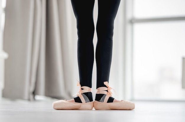 La vista del primo piano della ballerina ha raddrizzato le gambe rimanendo in prima posizione durante la lezione di danza in studio di coreografia