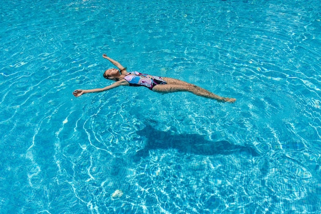 La vista della donna snella si trova su una superficie dell'acqua nella piscina di cristallo