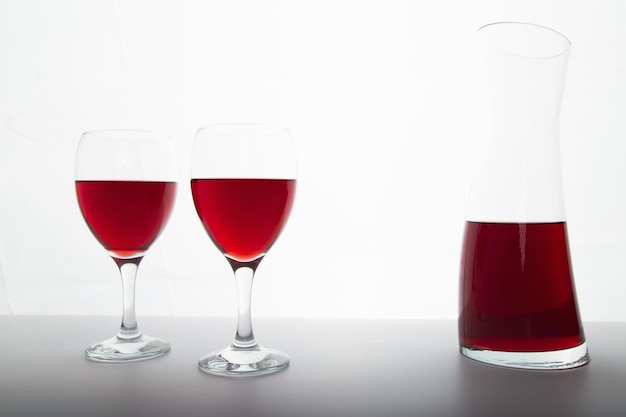 La vista dettagliata del primo piano di ciotole di vino rosso e caraffa retroilluminata illuminata con luce di retromarcia include spazio per la copia