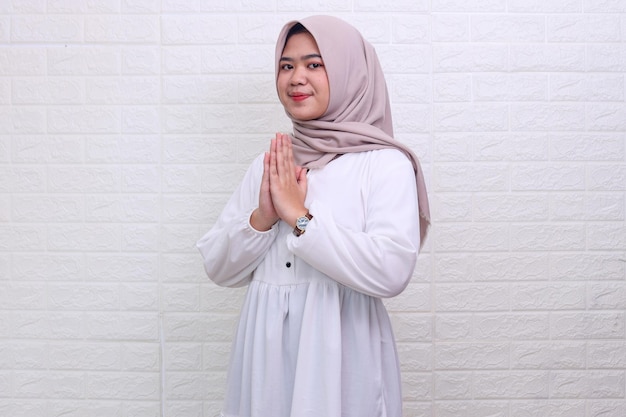 La vista laterale dell'adolescente musulmano asiatico che indossa l'hijab dà le mani di saluto per eid mubarak