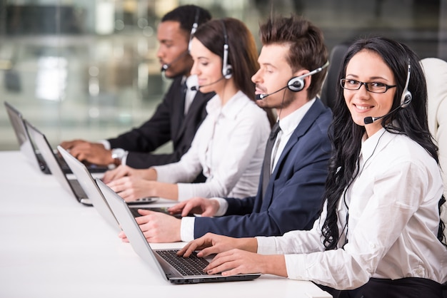 La vista laterale della linea di impiegati del call center sta sorridendo.