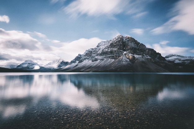 La vista panoramica del lago calmo contro le montagne innevate