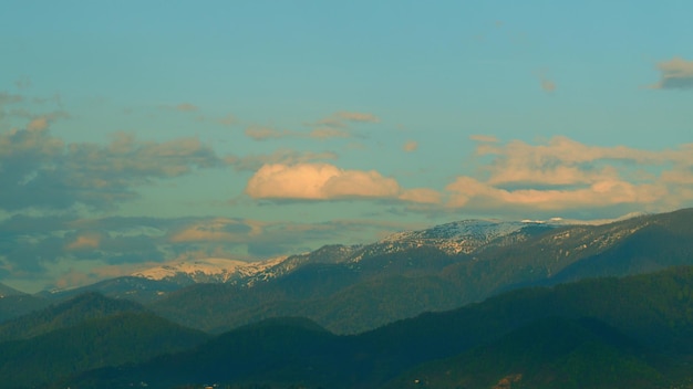 La vista panoramica del paesaggio dalla cima della montagna con nuvole e nuvole colorate dal sole del cielo blu