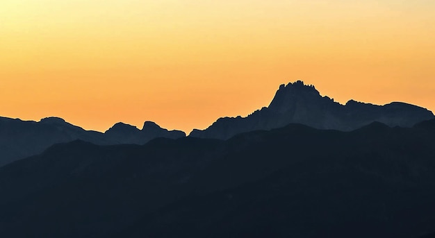 La vista panoramica delle montagne a silhouette contro il cielo arancione