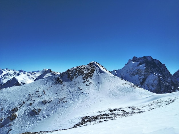 La vista panoramica delle montagne innevate contro un cielo azzurro limpido