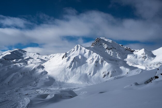 La vista panoramica delle montagne innevate contro un cielo nuvoloso