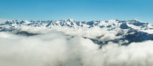 La vista panoramica delle montagne innevate di inverno varia in nuvole in Abkhazia al fondo del cielo blu