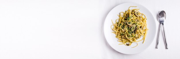 La vista superiore degli spaghetti di ostrica è servito in piatto bianco sulla tovaglia bianca. Con lo spazio della copia