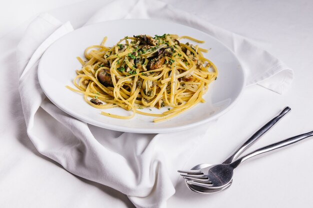 La vista superiore degli spaghetti di ostrica è servito in piatto bianco sulla tovaglia bianca.