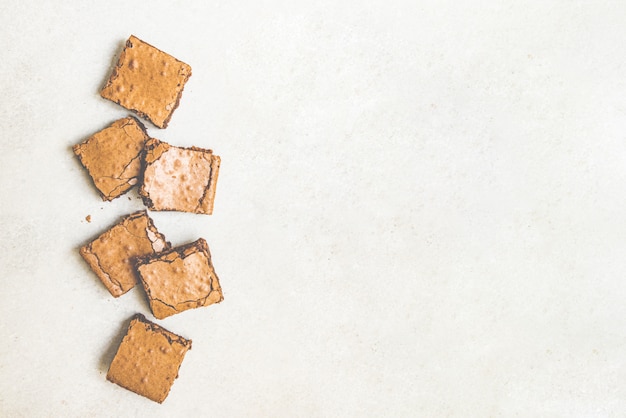 La vista superiore del dolce fatto in casa appena sfornato del brownie ha tagliato nei quadrati su rustico bianco.