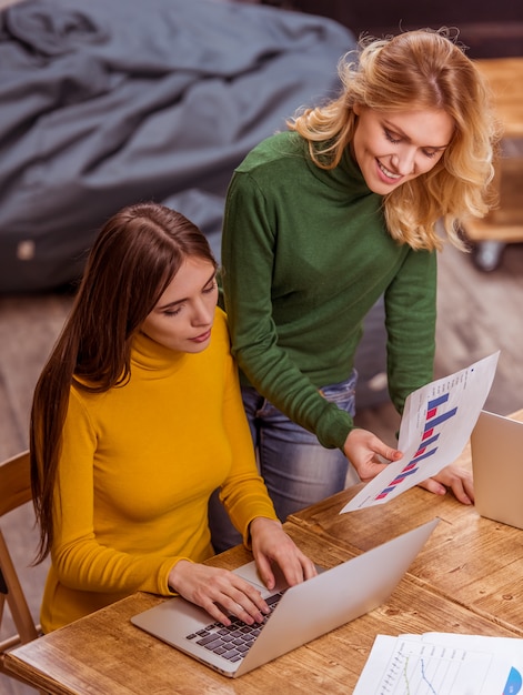 La vista superiore di due belle ragazze sta usando il computer portatile.