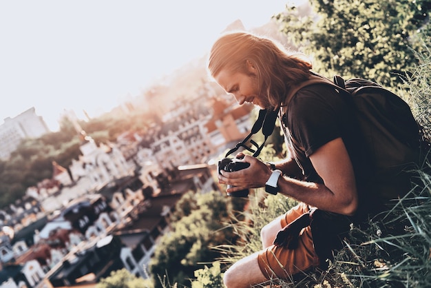 La vita è piena di bellezza. Giovane in abbigliamento casual che usa la macchina fotografica e sorride