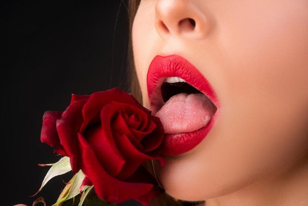 Labbra con primo piano rossetto Bella donna labbra con rosa Donna con macro rosa rossa su sfondo nero