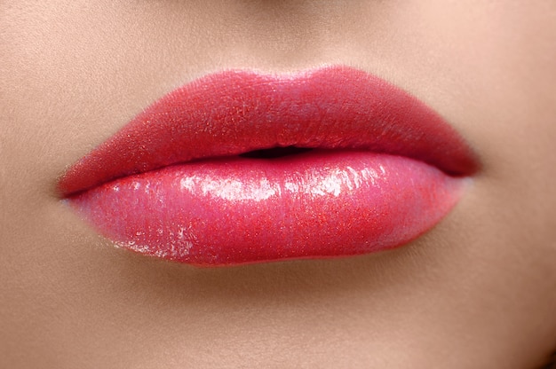 Labbra della donna ricoperte di lipgloss rosso.